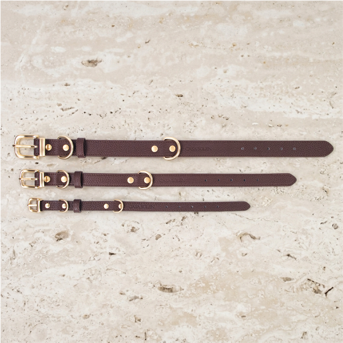 Three chestnut leather collars in various sizes with matte gold hardware