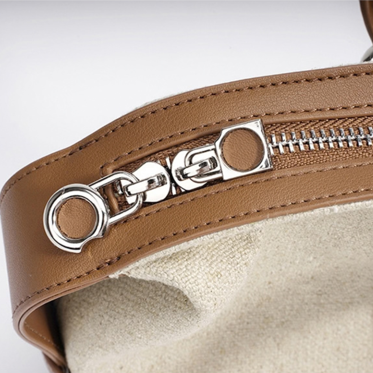 Metal zipper pulls on cognac leather edge for oat canvas handbag