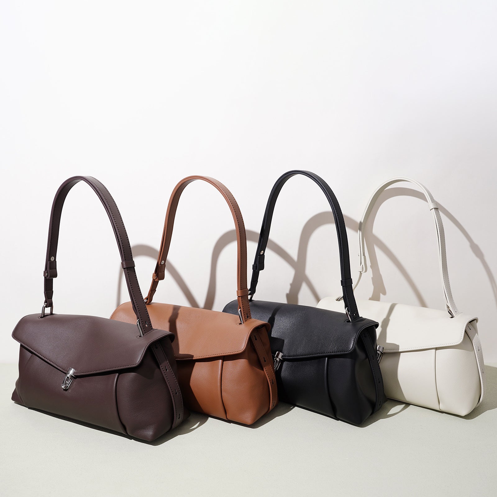 Leather handbags in multiple colors—espresso, sienna, onyx, oat—front flap clasps