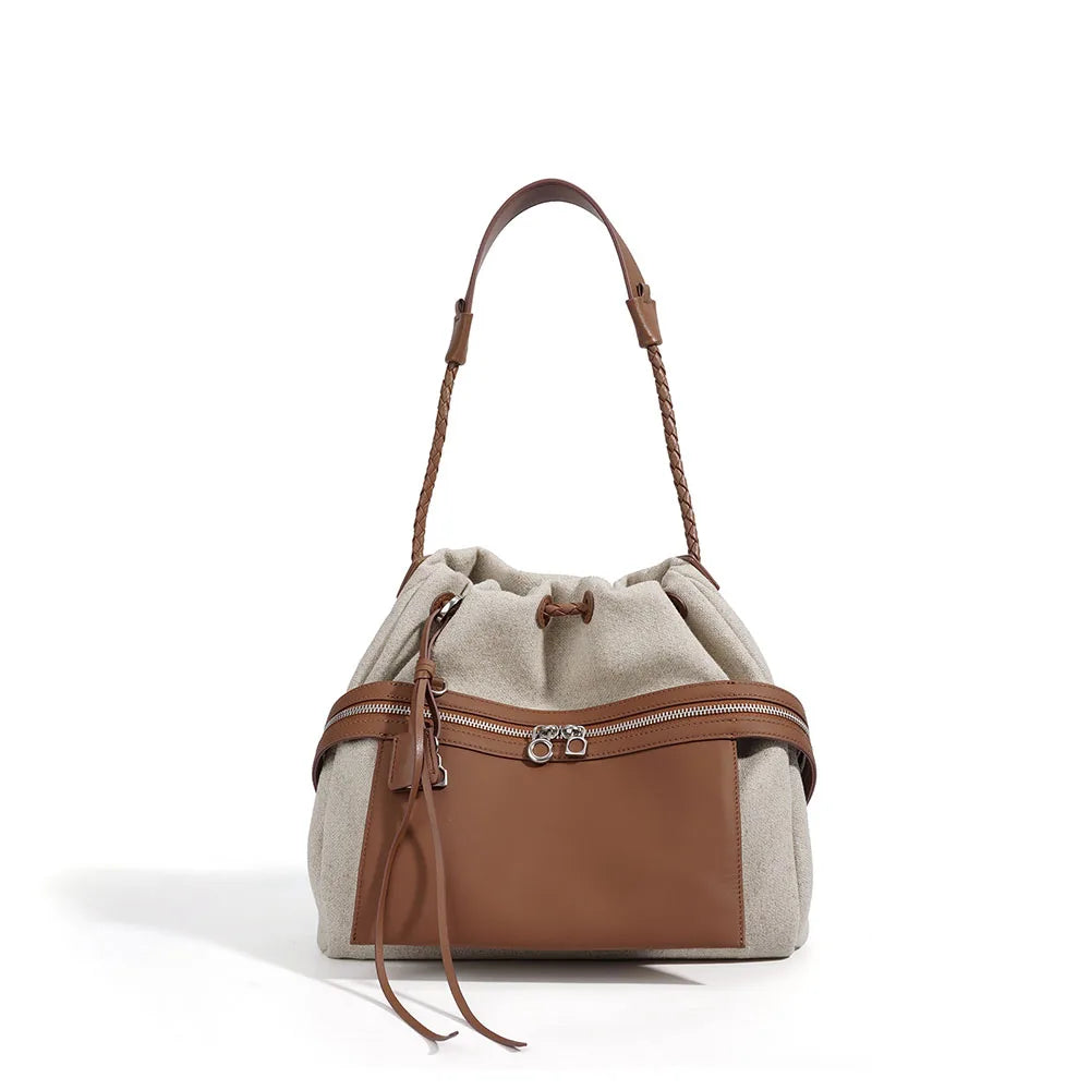 Oat canvas bucket bag with cognac leather trim, drawstring top, and zip front pocket