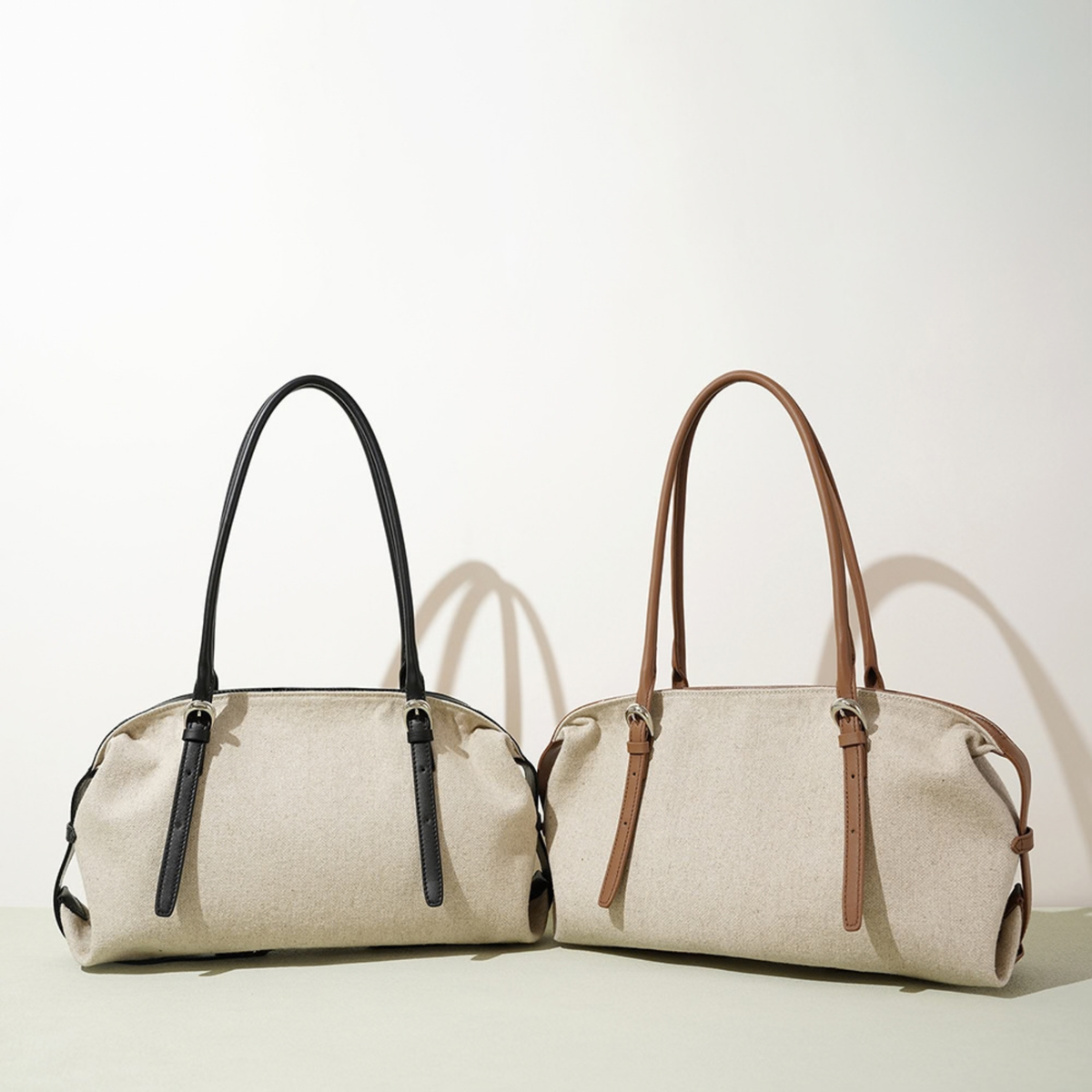 Two leather tote bags in oat with black and cognac accents, double handles