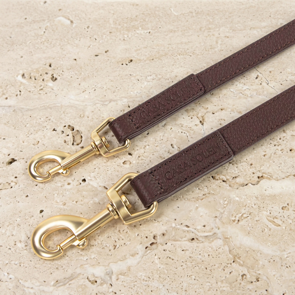 Chestnut leather dog leash detail with matte gold swivel clips and embossed Casa Solen logo
