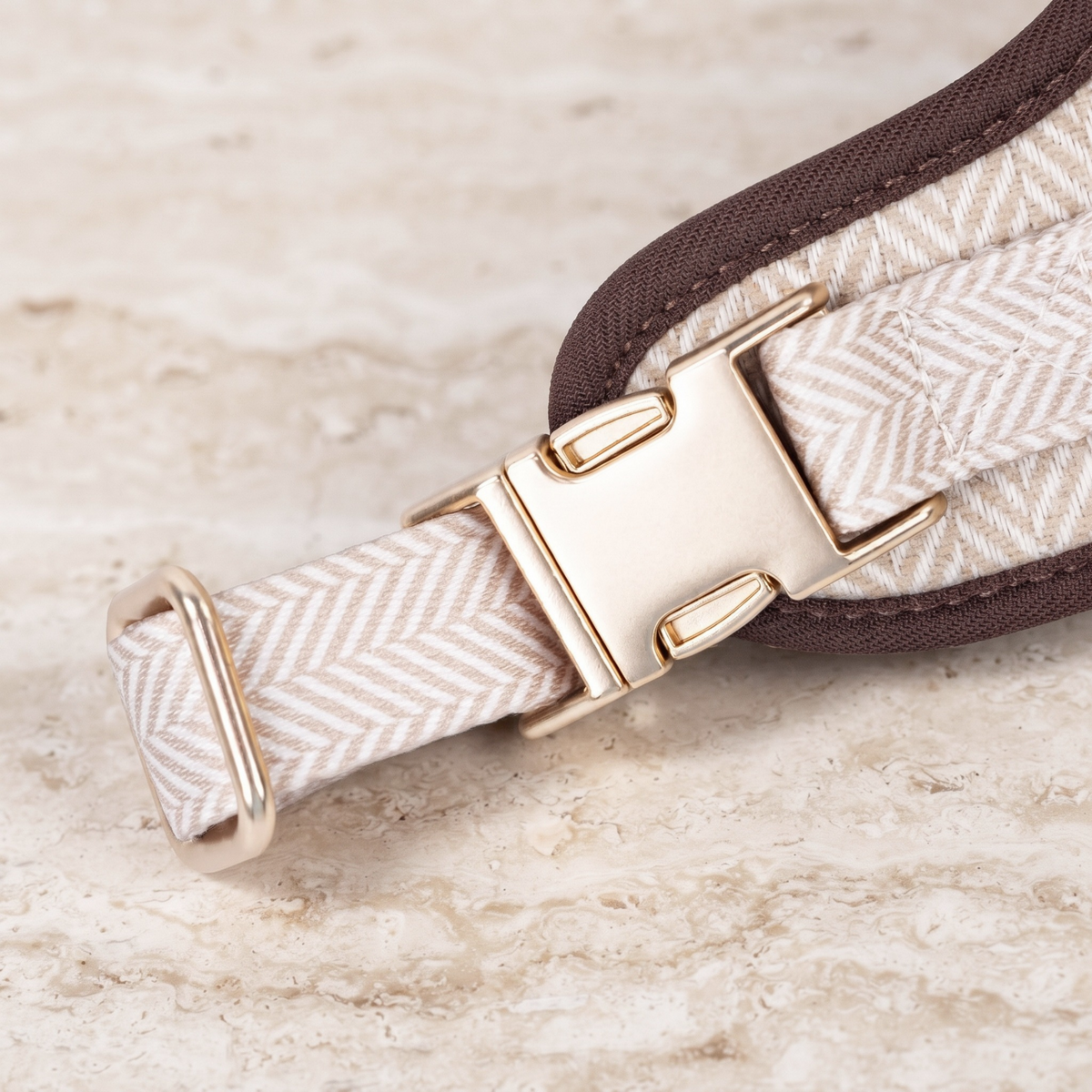 Herringbone dog harness strap close-up with gold-tone buckles and brown edge trim