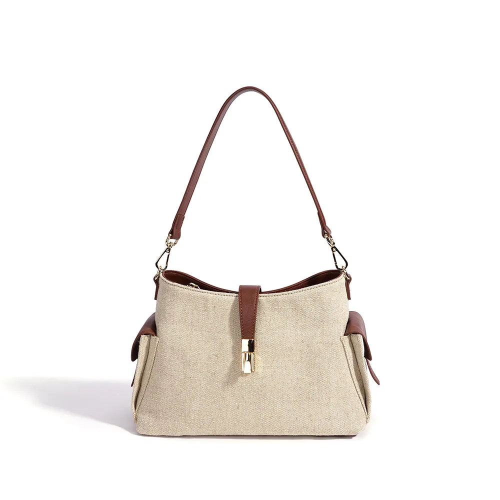 Cream canvas bag with brown leather shoulder straps, center zipper, and gold hardware