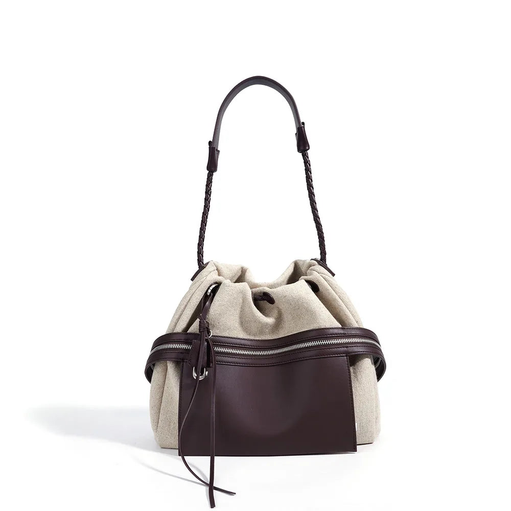 Two-tone leather bucket bag with drawstring top and brown front zip pocket, braided handles