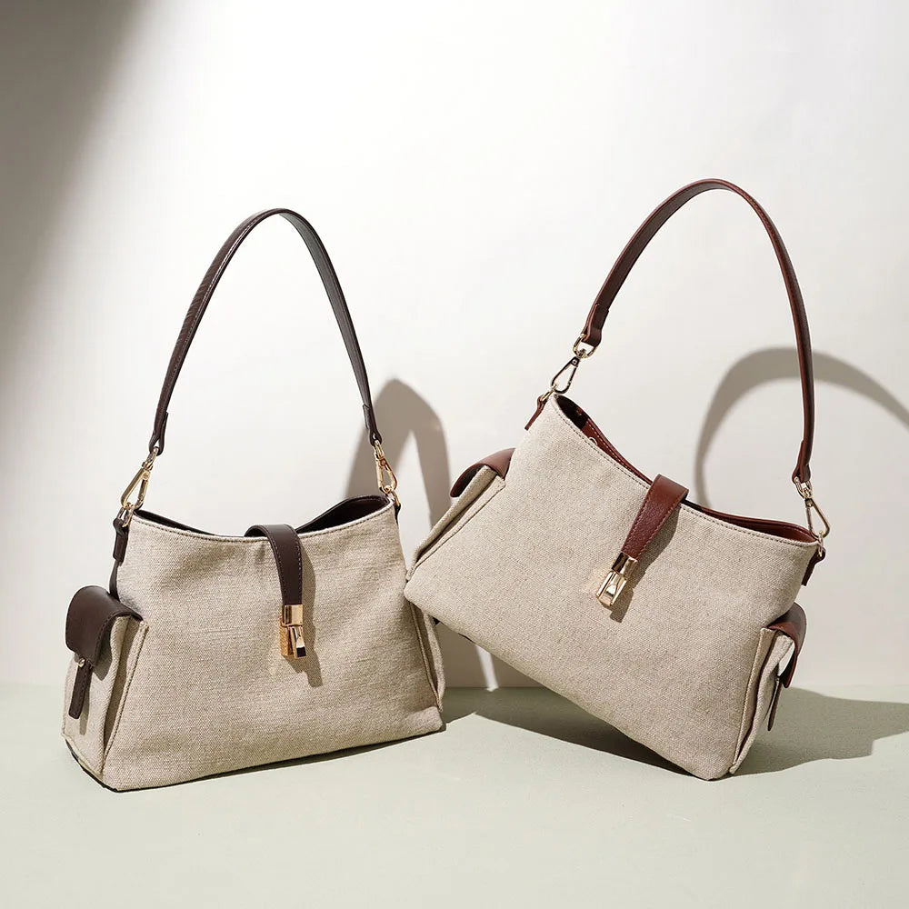 Cream canvas bag with brown leather trim, shoulder straps, and gold zipper detail