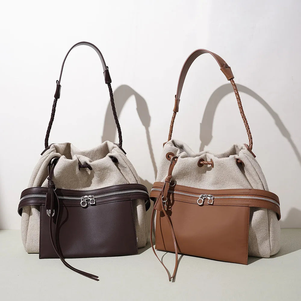 Two-tone leather bucket bag with drawstring top, brown front zip pocket, braided handles