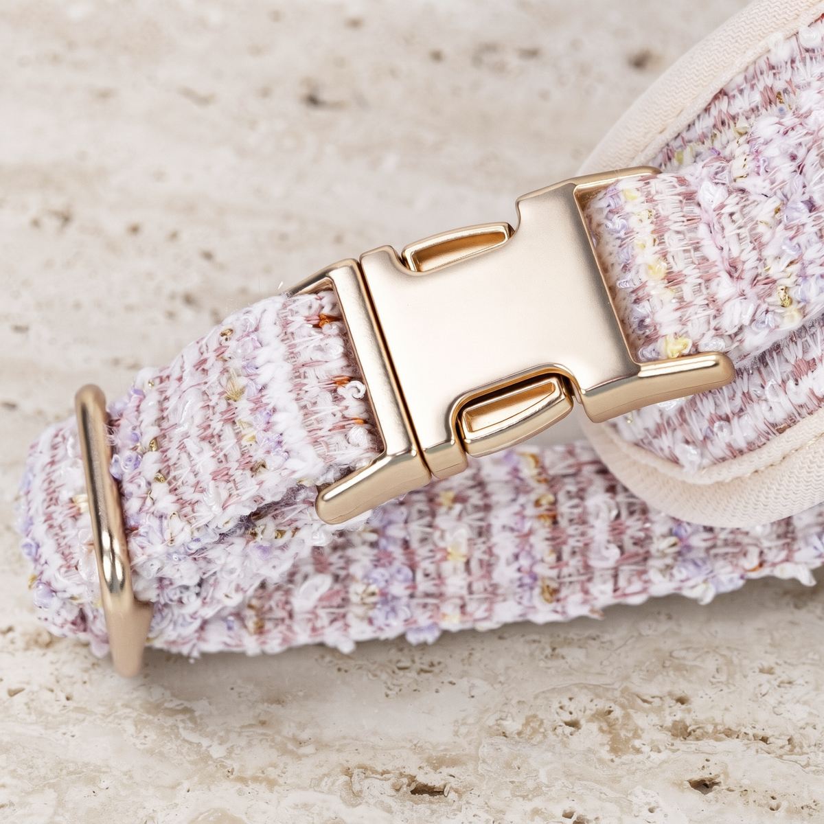 Close-up of rosewater tweed dog harness buckle hardware with stitched webbing.